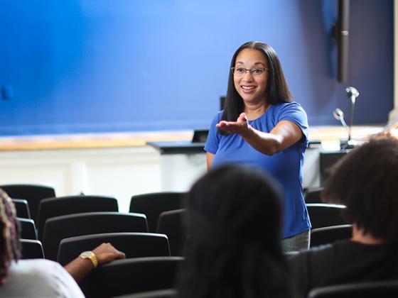 Female faculty member with her hand out teaching a class